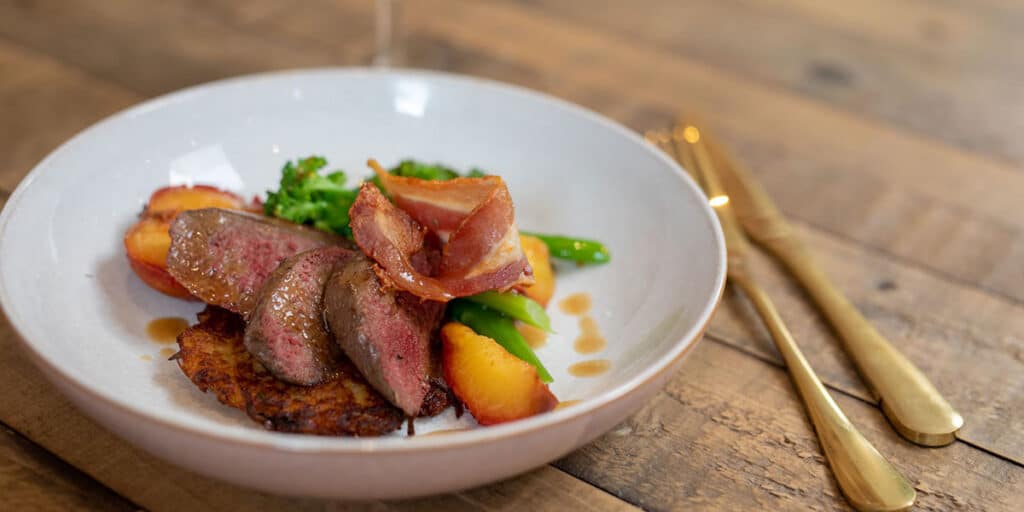 Grouse breasts with a potato rosti, roasted plums & bacon